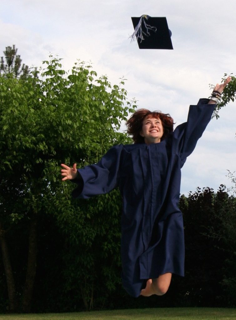 young-woman-at-graduation-throwing-cap-blue-robe