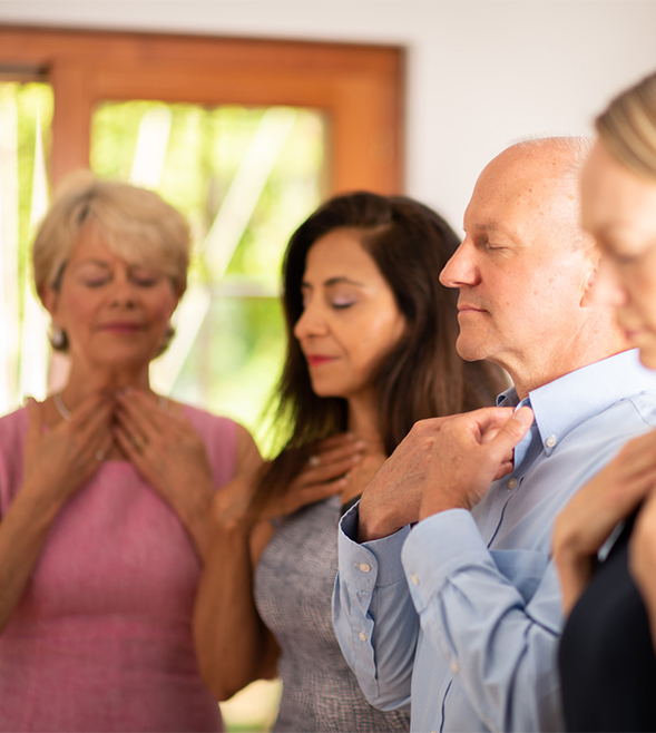 adults-meditation-group-with-teacher-coach-eyes-closed-hands-touching-neck