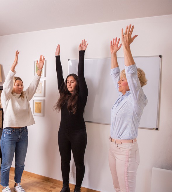 group-workshop-women-standing-reaching-arms-up-eyes-closed